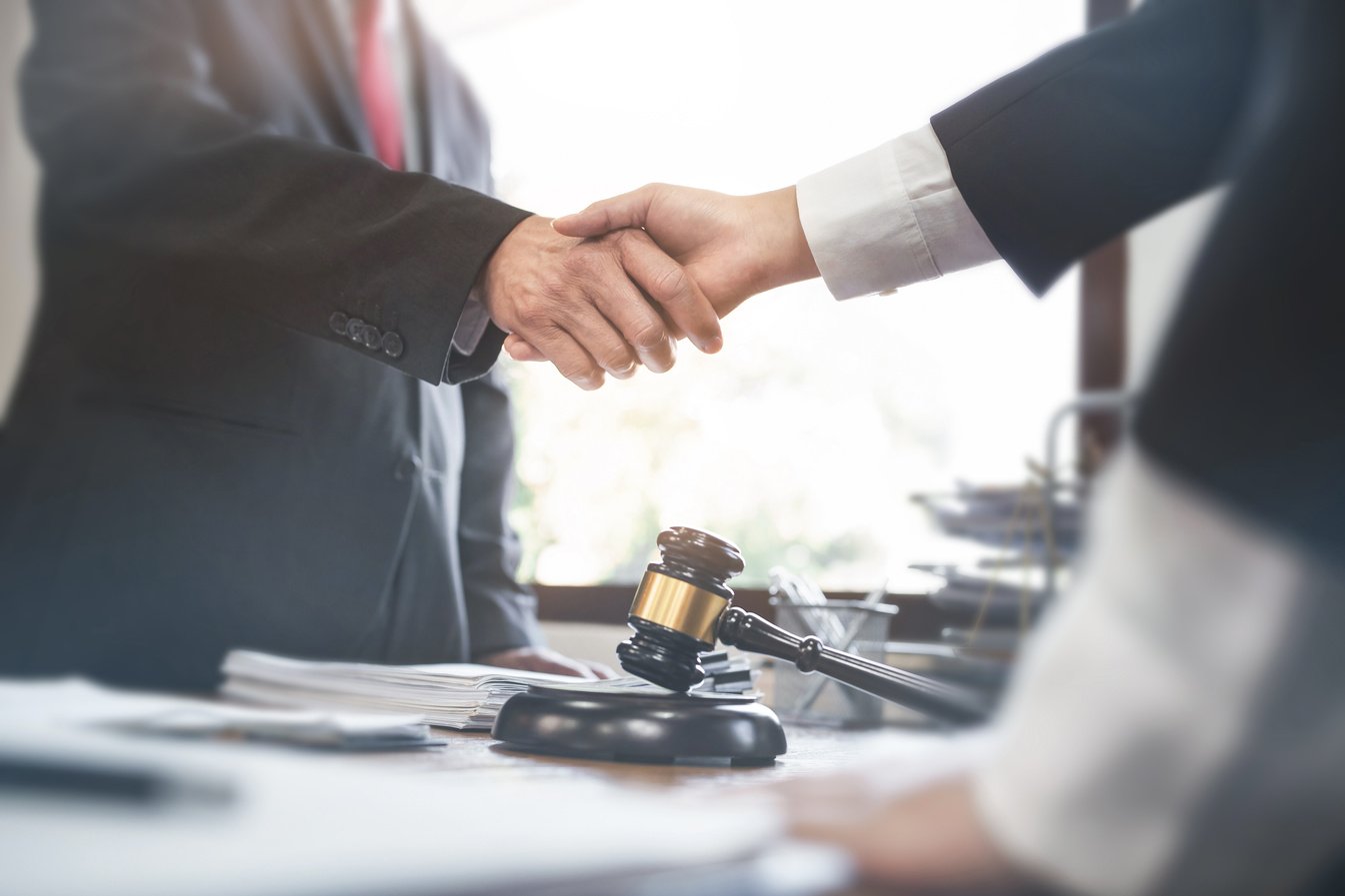 Lawyer consultant shaking hand with client in law firm.